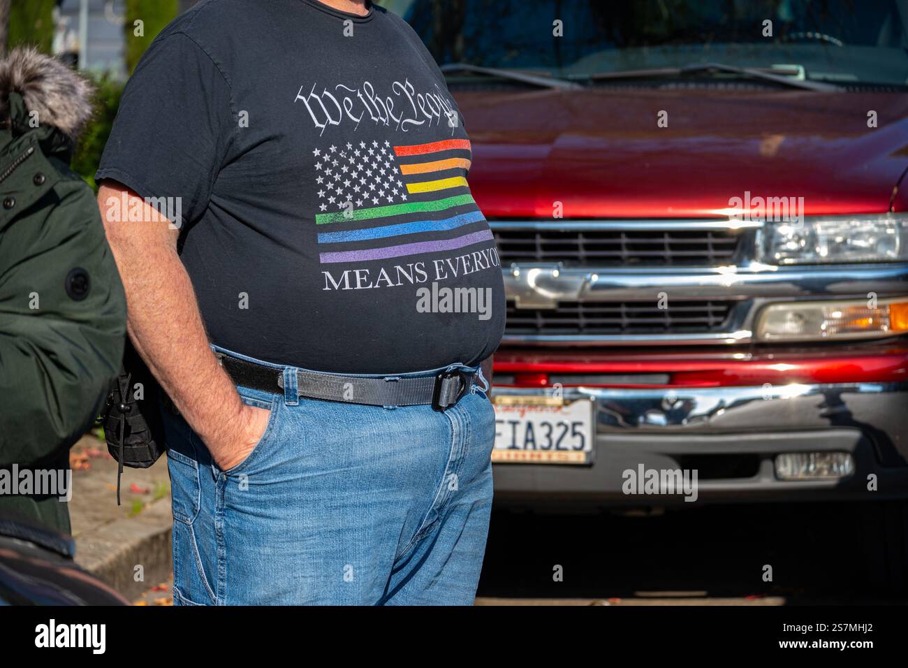 L'uomo al giorno della marcia della resistenza indossa una maglietta con bandiera arcobaleno americana e riferimento alla costituzione con parole che noi popolo intendiamo evento Foto Stock