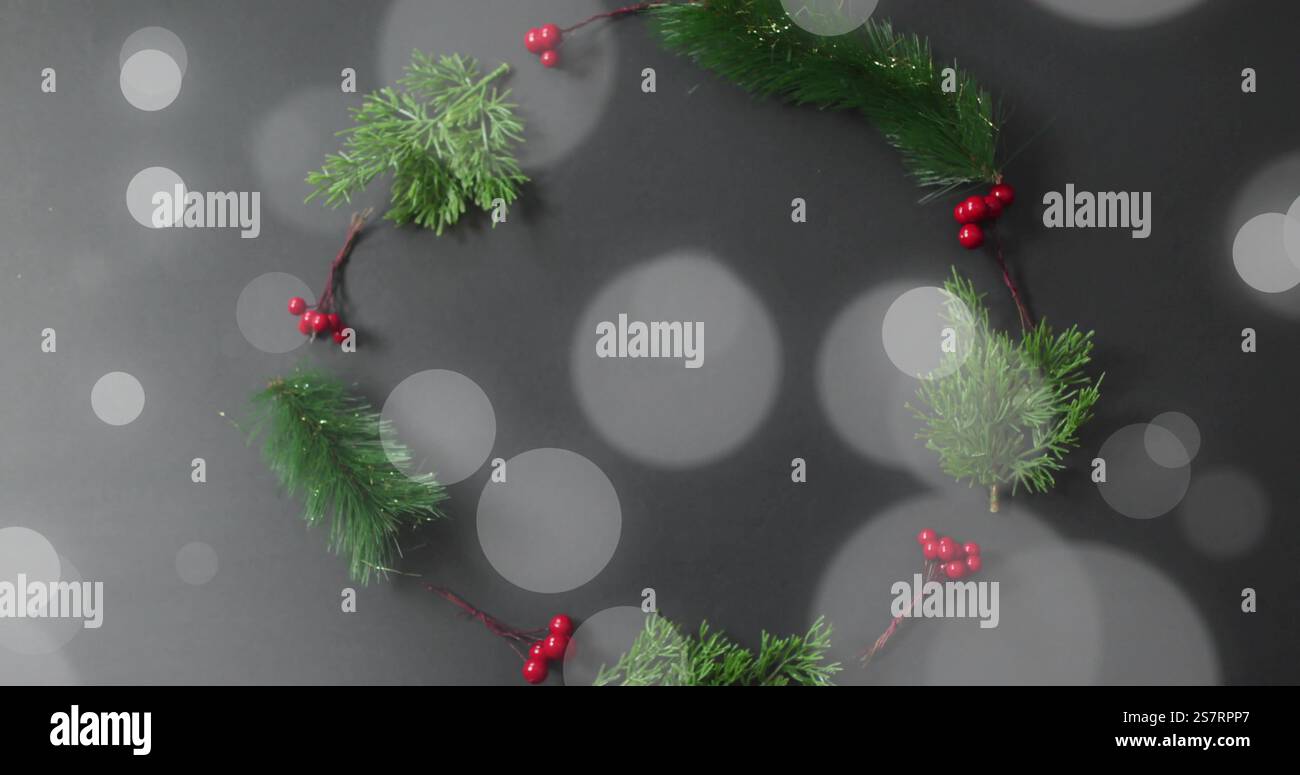 Corona di Natale con bacche rosse e rami di pino verde sopra l'immagine delle luci bokeh Foto Stock