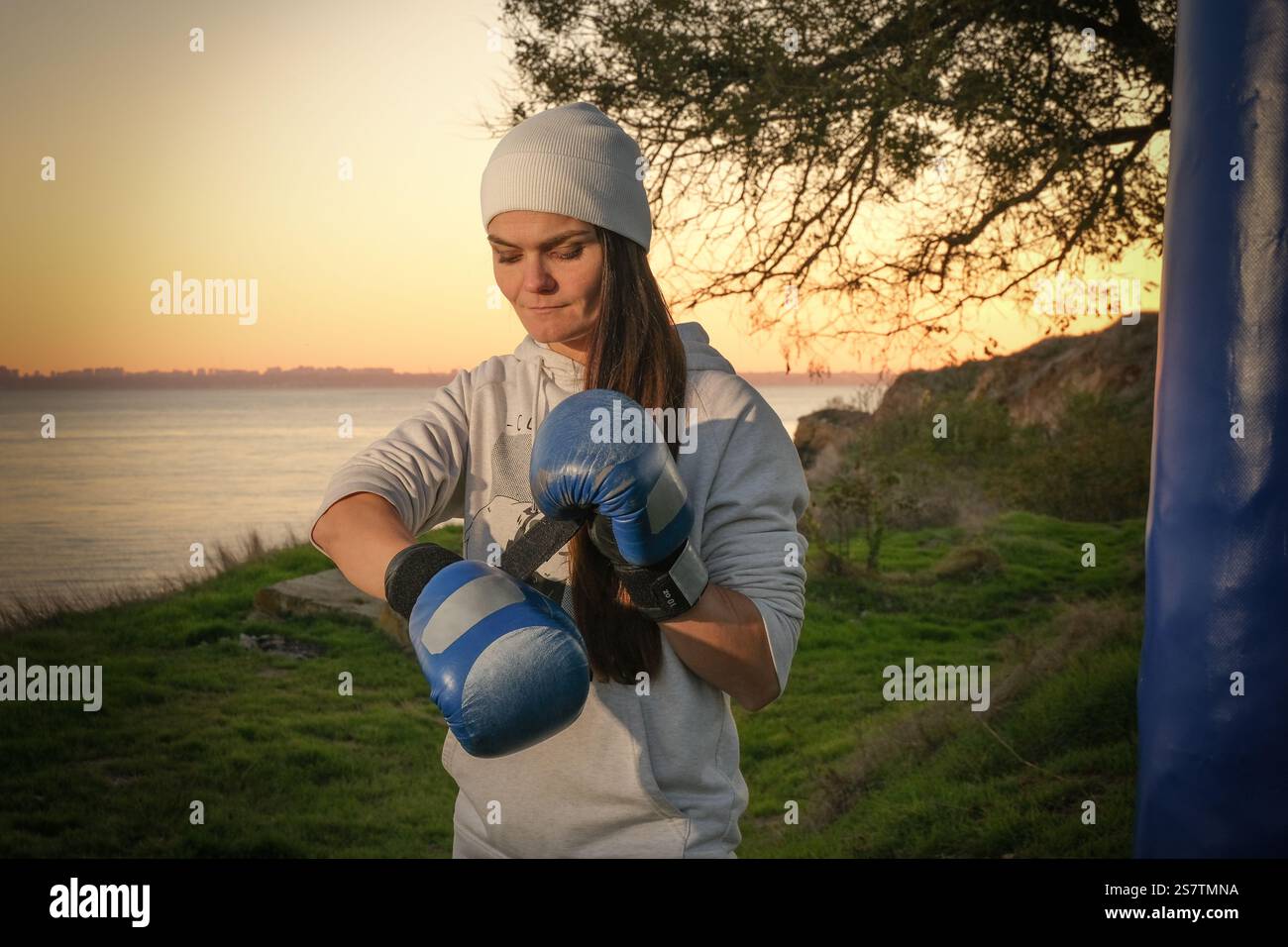 Giovane pugile che sbottonava i guanti prima di boxe in mare Foto Stock