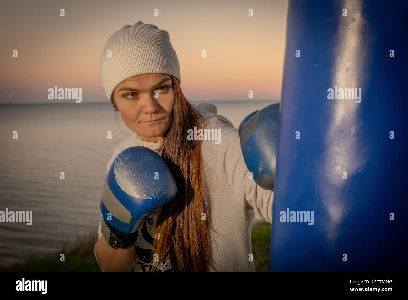 Giovane donna che posa con guanti da boxe e borsa da pugno Foto Stock