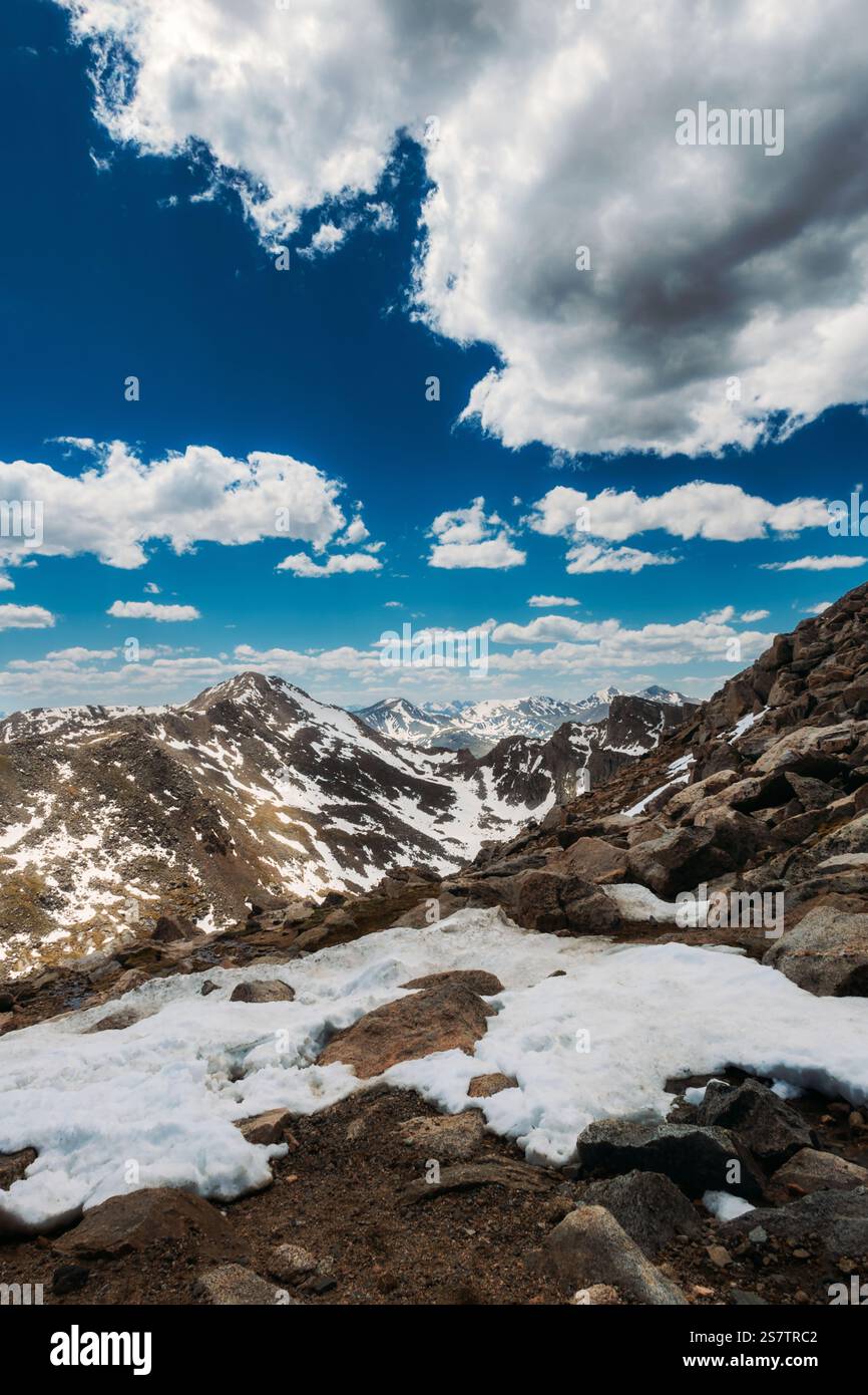 Cima delle Montagne Rocciose con soffici nuvole e cielo blu Foto Stock