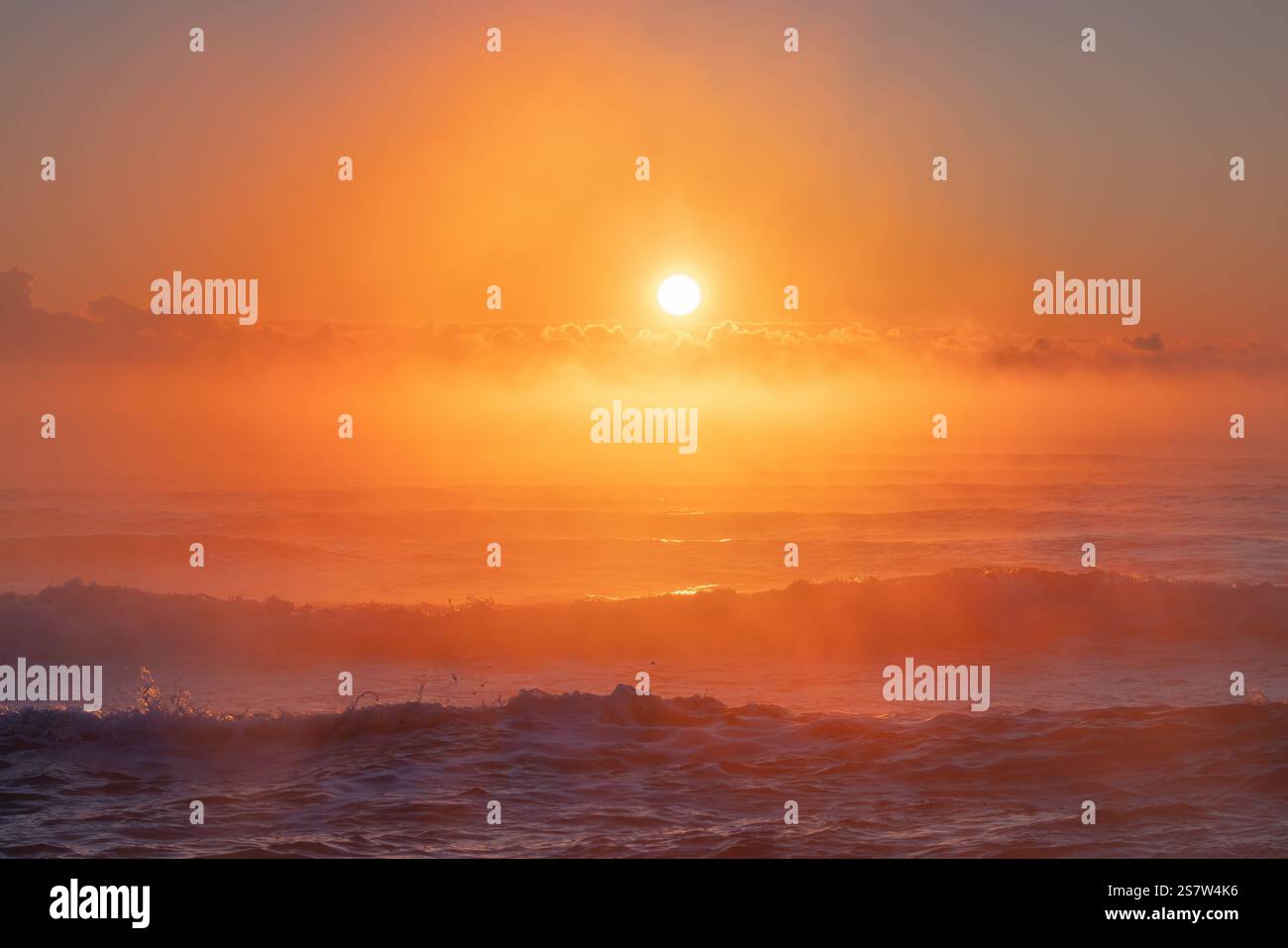Magnifica alba sulle onde dell'Oceano con tranquilla luce arancione e nebbia Foto Stock