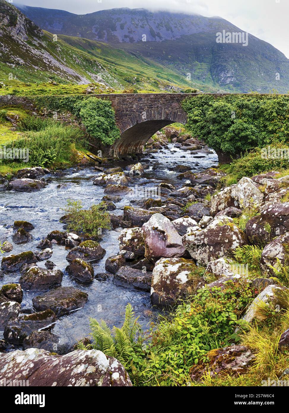 Ruscello, ponte ad arco, ponte in pietra Wishing Bridge, passo di montagna Gap of Dunloe, Killarney, strada panoramica Ring of Kerry, penisola di Iveragh, contea di Kerr Foto Stock