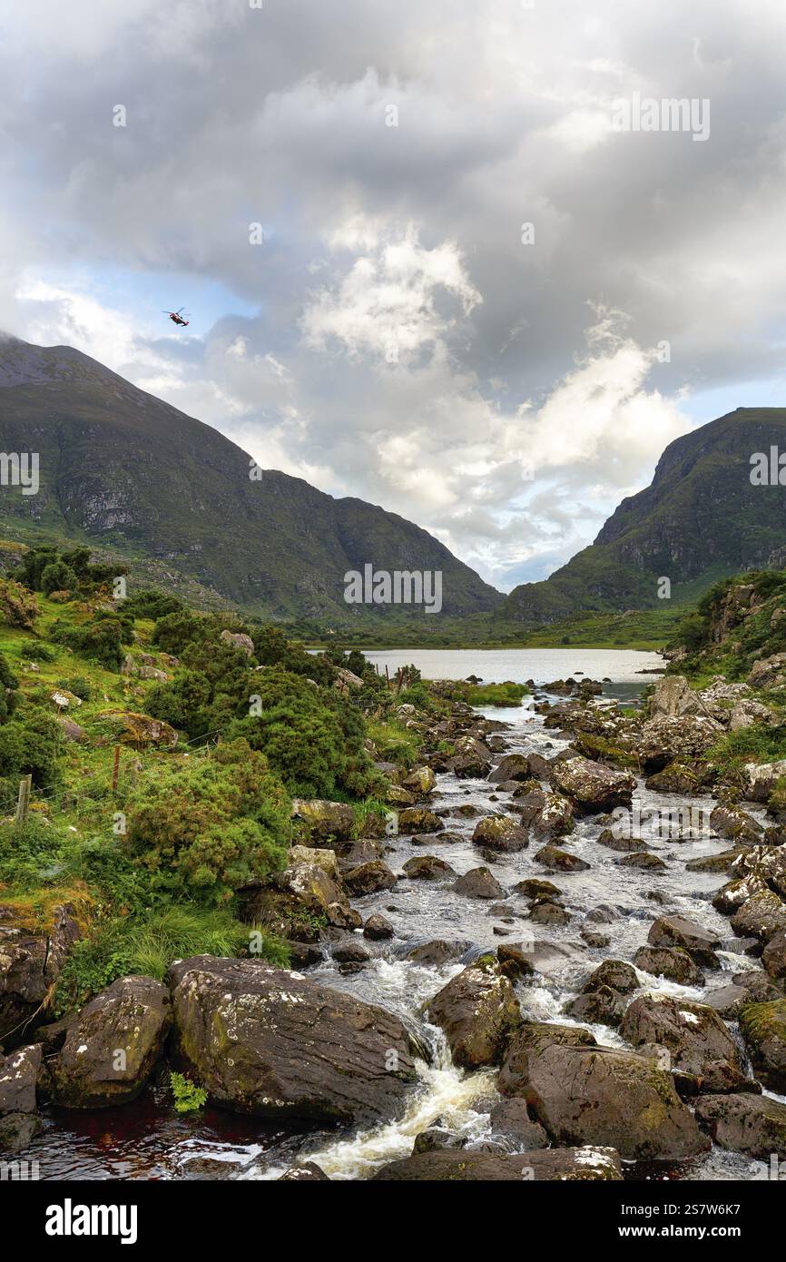 Ruscello, lungolago, volo in elicottero di salvataggio al crepuscolo, passo di montagna Gap of Dunloe, Killarney, strada panoramica Ring of Kerry, penisola di Iveragh, contea di Kerry Foto Stock