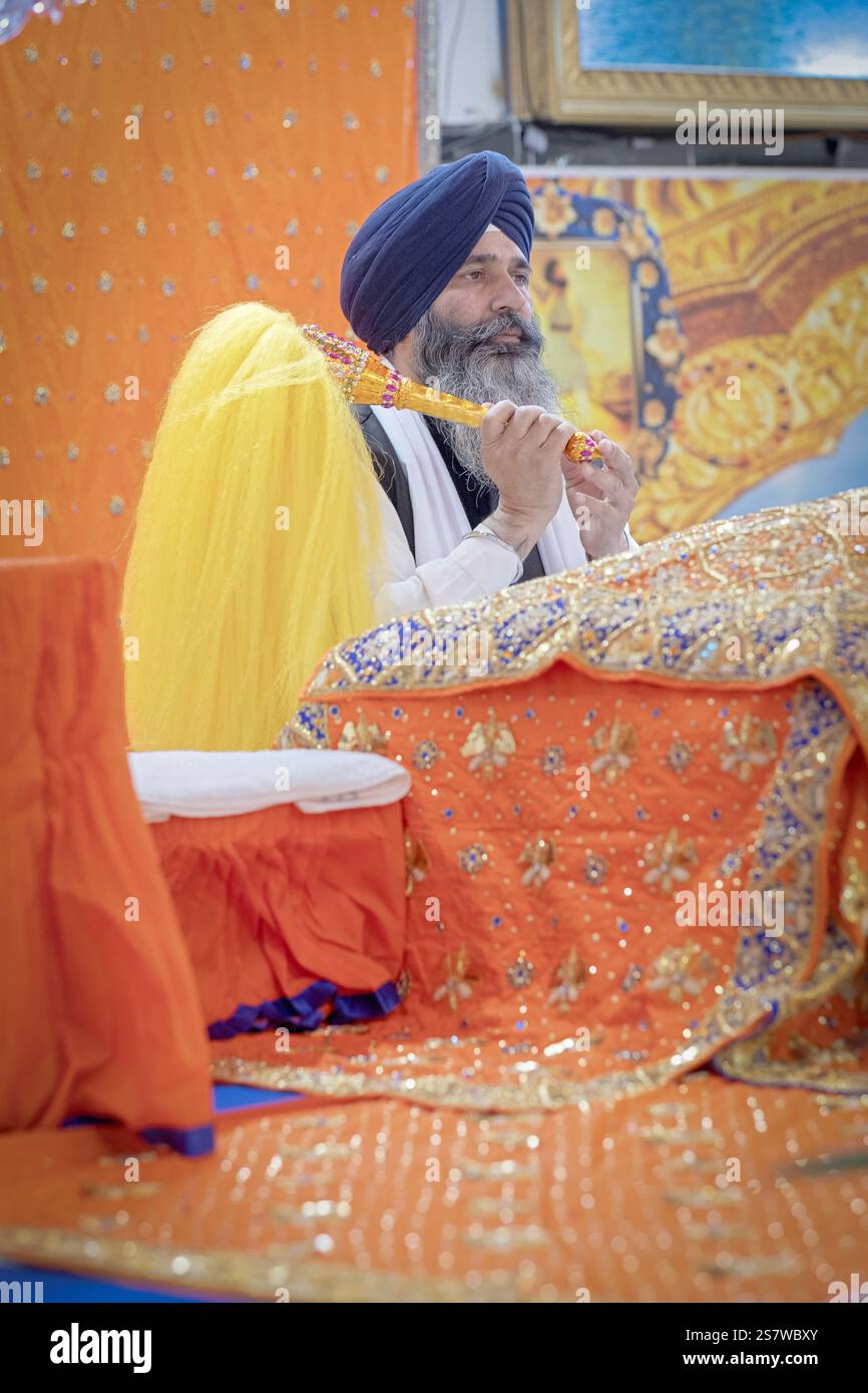 Un prete sikh sventolò una bandiera gialla, chaur sahib, durante i servizi in un tempio di Richmond Hill, Queens, New York. Foto Stock