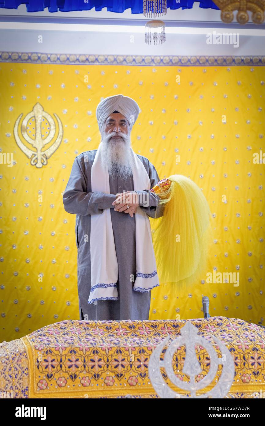 Un prete Sikh a tiene un Chaur Sahib per sventolare la bibbia in modo riverente. In un tempio a South Richmond Hill, Queens, New York. Foto Stock