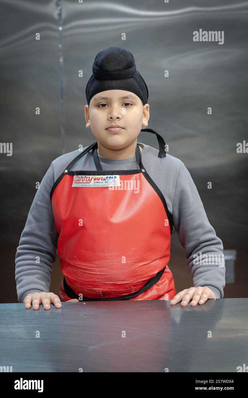 Un'adolescente Sikh che fa volontariato nella cucina di langar di un tempio nel Queens, New York. Foto Stock
