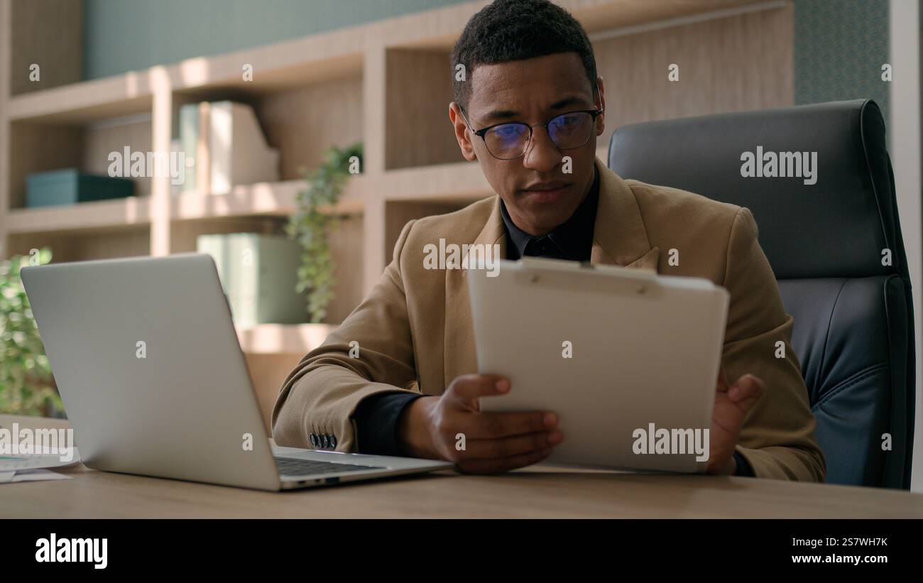 Uomo d'affari contabile afroamericano lavoratore d'ufficio maschile scrivere dati finanziari piano di analisi strategia uomo d'affari concentrato lavorare con computer portatile Foto Stock