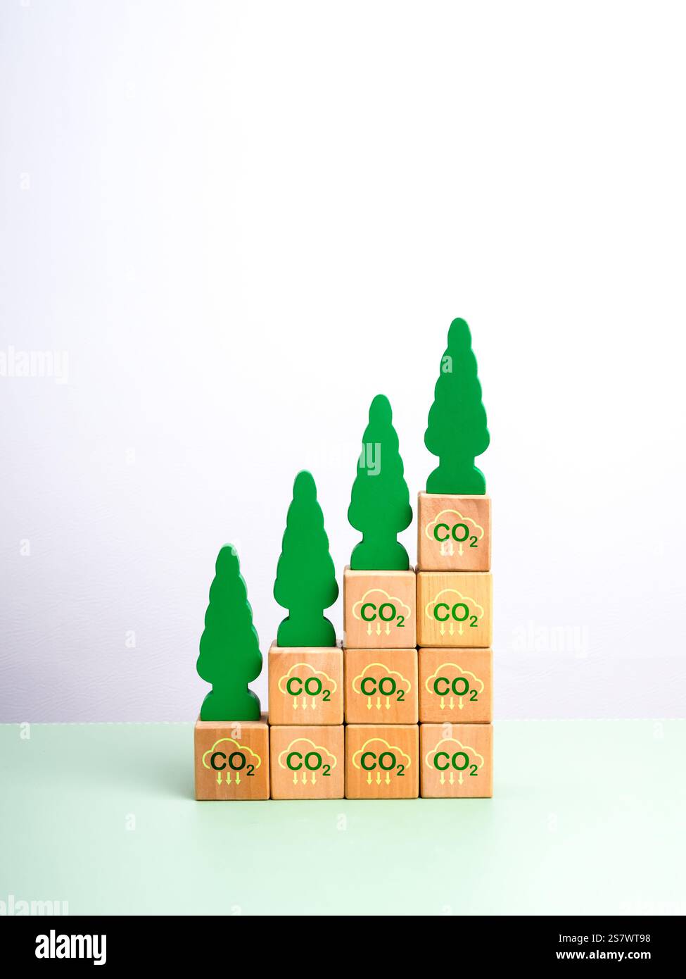 Riduzione delle emissioni di carbonio, concetto di sostenibilità ambientale. Alberi verdi in crescita, giocattoli di legno su blocchi di cubo di legno con simbolo di riduzione di co2, come gro Foto Stock