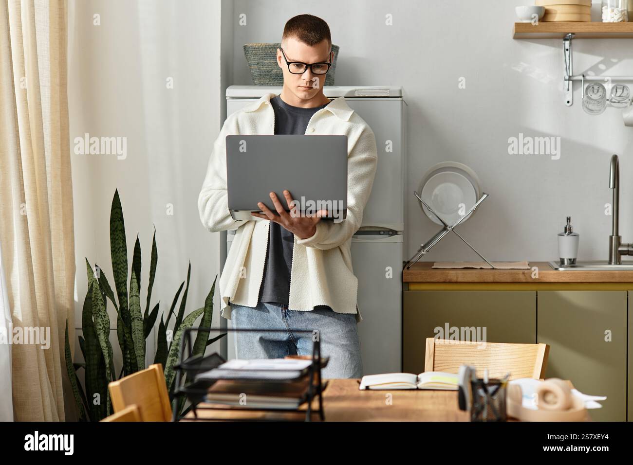 Un bel giovane si occupa di lavoro a distanza mentre si trova in un elegante appartamento. Foto Stock