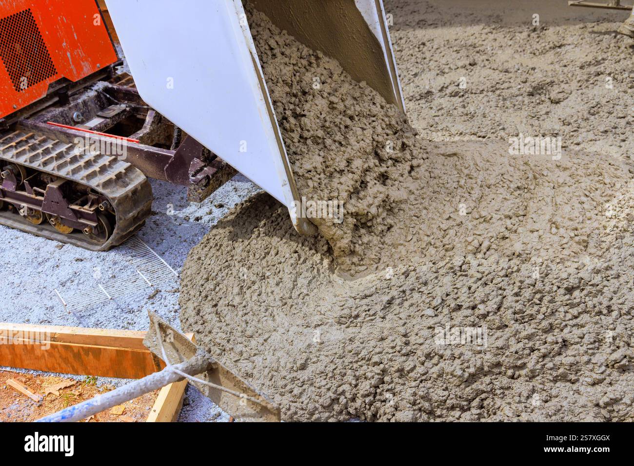 L'operatore versa cemento fresco da un autocarro in gomma su una superficie preparata per nuove fondamenta Foto Stock