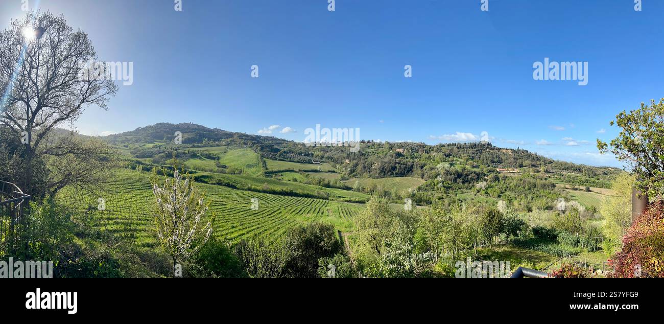 Vista panoramica di Montepulciano, un'affascinante città collinare in Toscana, circondata da montagne ondulate e lussureggianti paesaggi primaverili sotto un cielo blu - Immagine stock catturata con smartphone