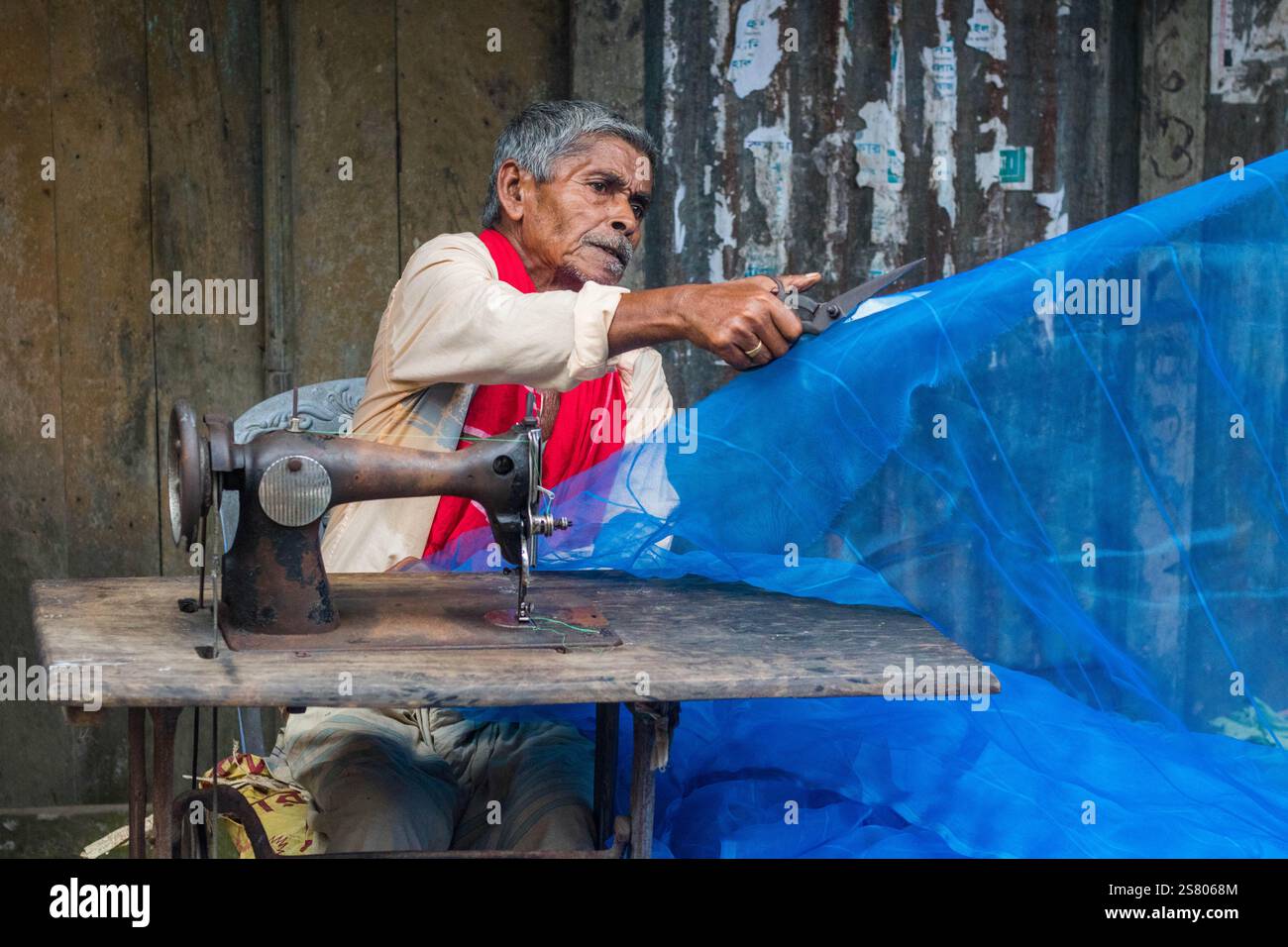 Cumilla, Bangladesh - 24 ottobre 2023: Un vecchio che cucisce tessuti in un negozio di strada che sarta il mercato locale. Foto Stock Cumilla, Bangladesh - 24 ottobre 2023: Un vecchio che cucisce tessuti in un negozio di strada che sarta il mercato locale. Foto Stock