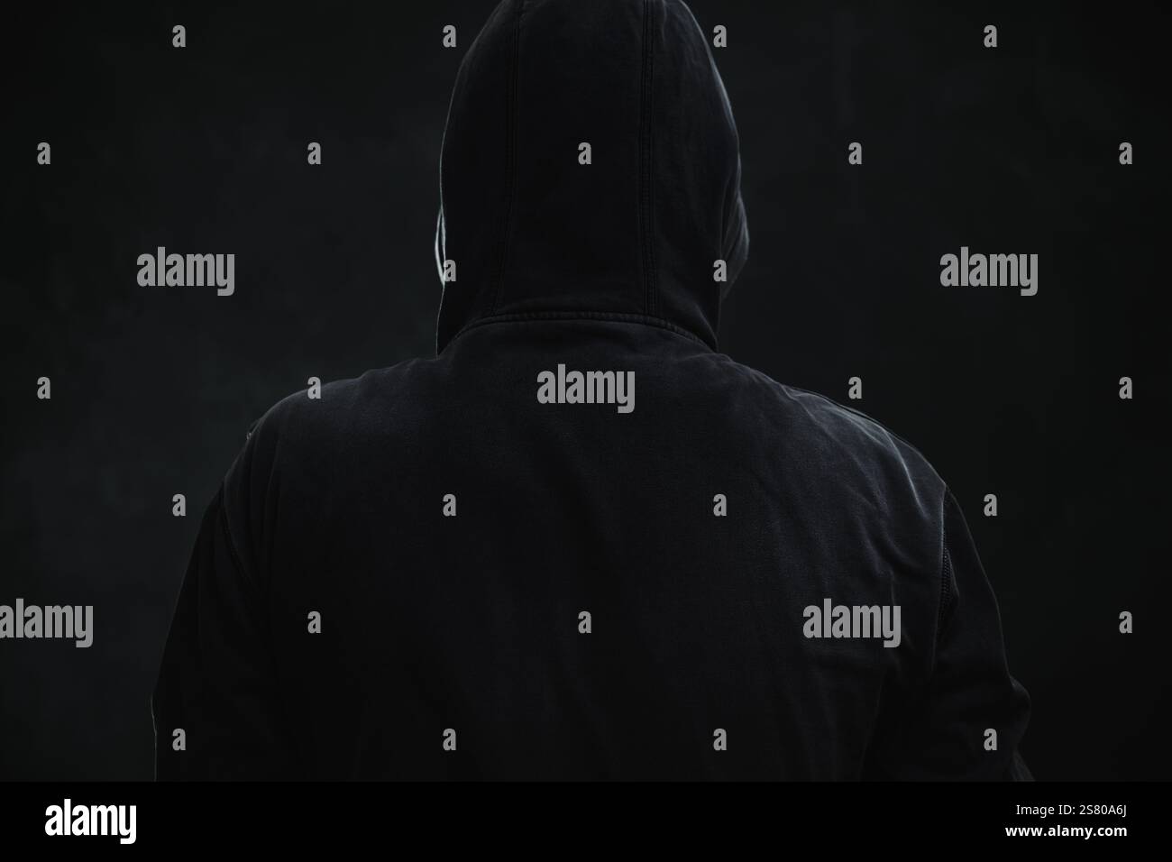 Cyber criminale o hacker irriconoscibile che indossa una giacca nera con cappuccio, ritratto basso, messa a fuoco selettiva Foto Stock