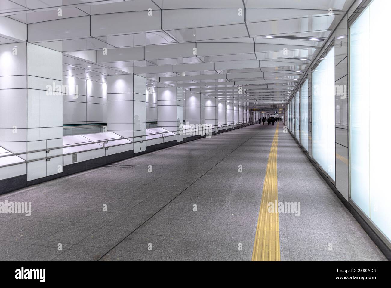 Moderno corridoio vuoto della metropolitana con pavimentazione tattile e pannelli illuminati Foto Stock