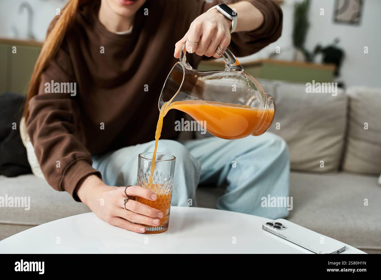 Un momento luminoso e informale mentre un giovane uomo elegante versa il succo nella sua accogliente casa. Foto Stock Un momento luminoso e informale mentre un giovane uomo elegante versa il succo nella sua accogliente casa. Foto Stock