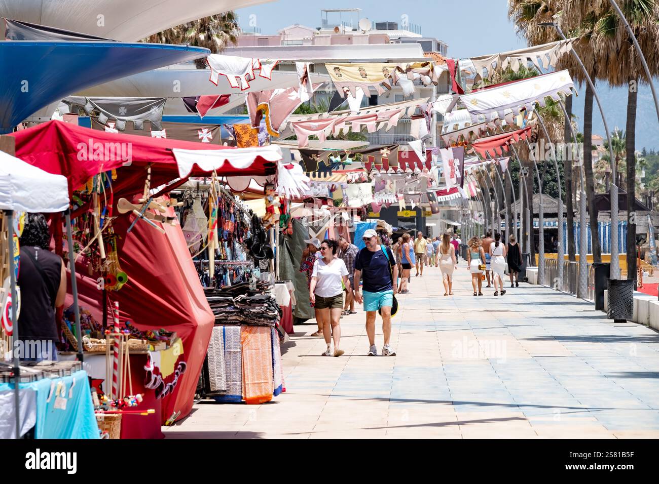 Estepona, Spagna. Ho una vista sul lungomare lungo il lungomare. Le bancarelle del mercato fiancheggiano il marciapiede con i turisti che si godono il caldo sole Foto Stock