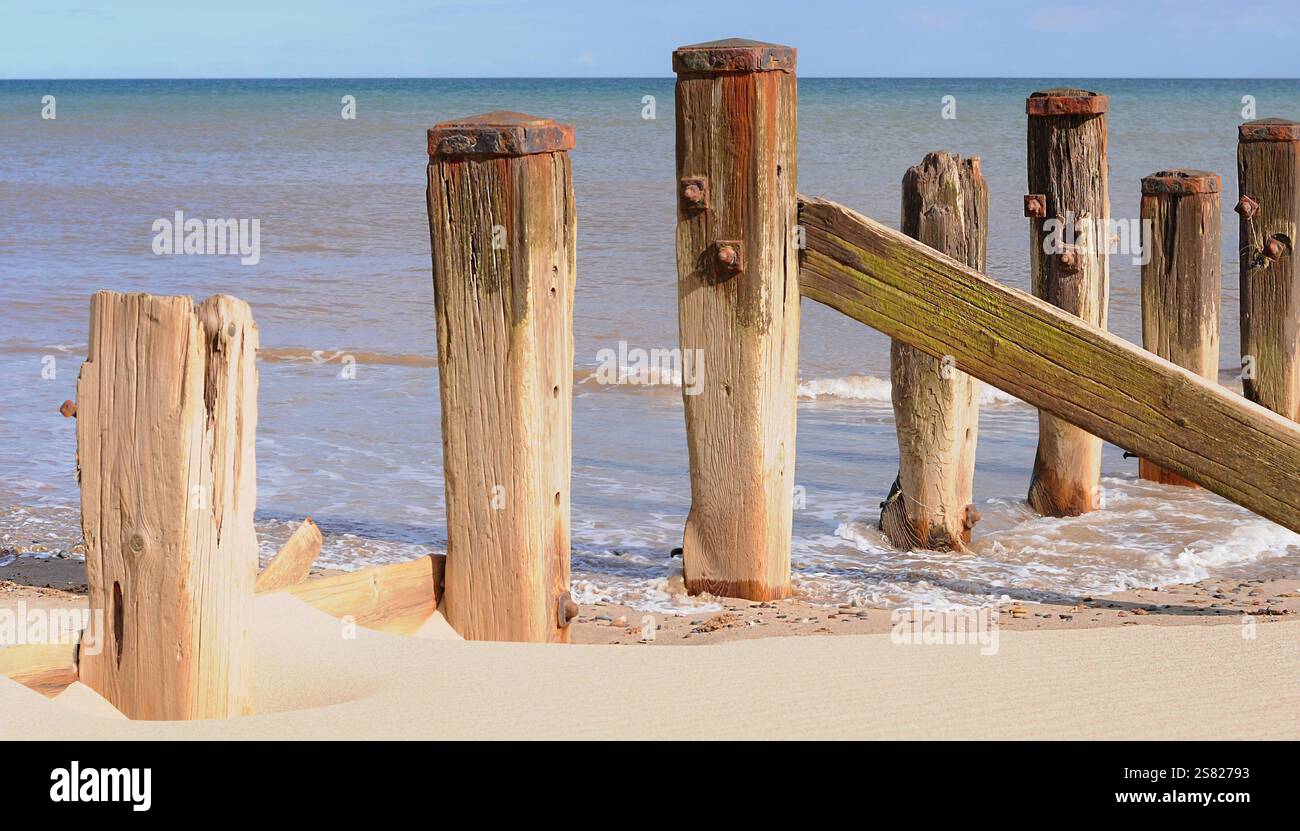 Gli intemperie di legno sulla spiaggia di Surn Point. Costa storica. Sabbia e onde. Luce del giorno. Immagine luminosa. Oggetti sfocati. Easington, East Yorkshire, Regno Unito Foto Stock