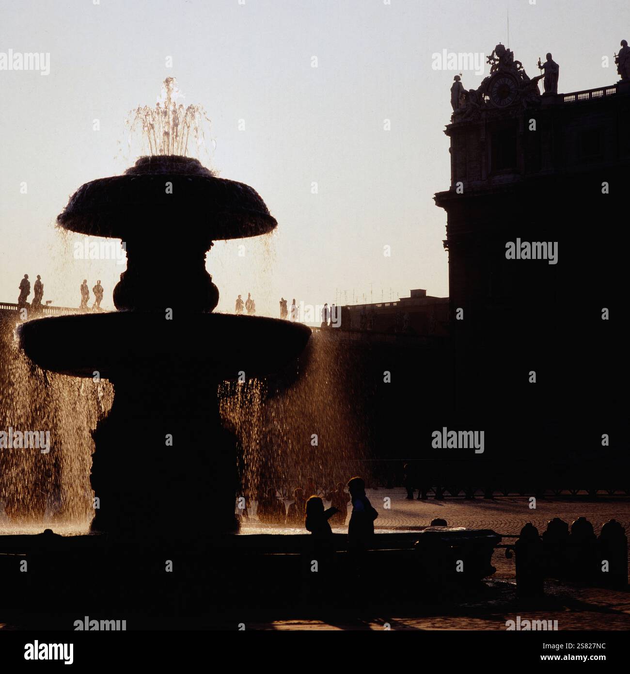 Wasser plätschert aus dem Brunnen auf dem Petersplatz mit dem Apostolischen Palast im Hintergrund bei Sonnenuntergang, Italien um 1977. Foto Stock