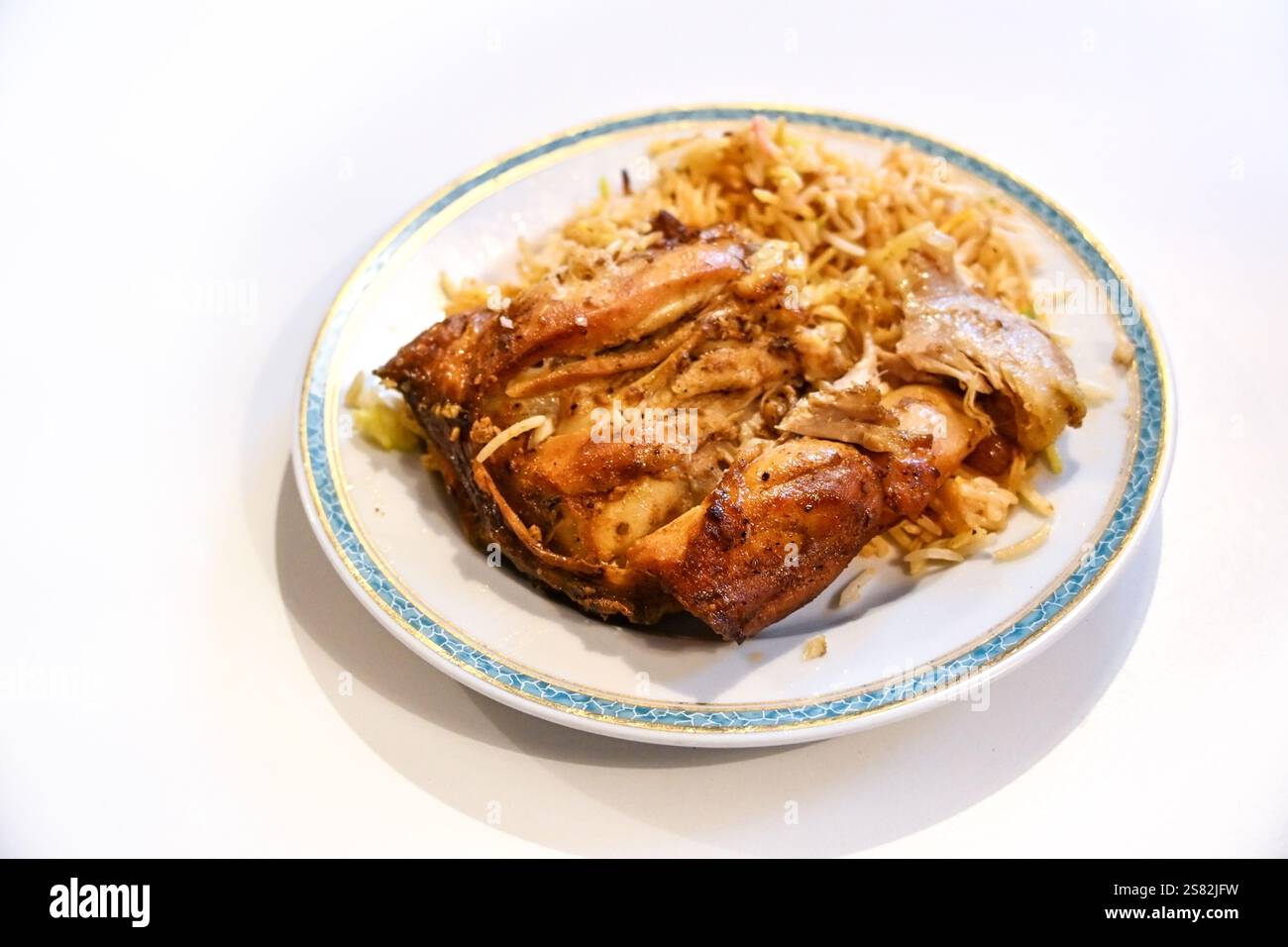 Pollo con biryani, il tradizionale piatto asiatico di riso piccante fritto, porzione su un piatto e su un tavolo leggero, spazio copia, messa a fuoco selezionata, reparto stretto Foto Stock