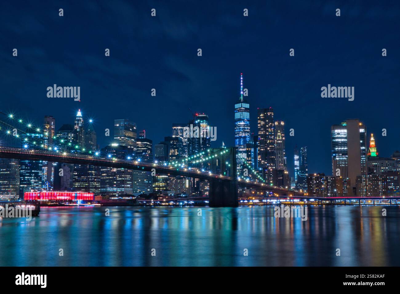Vista notturna del Ponte di Brooklyn e dello skyline di Lower Manhattan a New York City. L'iconico ponte è illuminato da luci accese, creando una S. Foto Stock