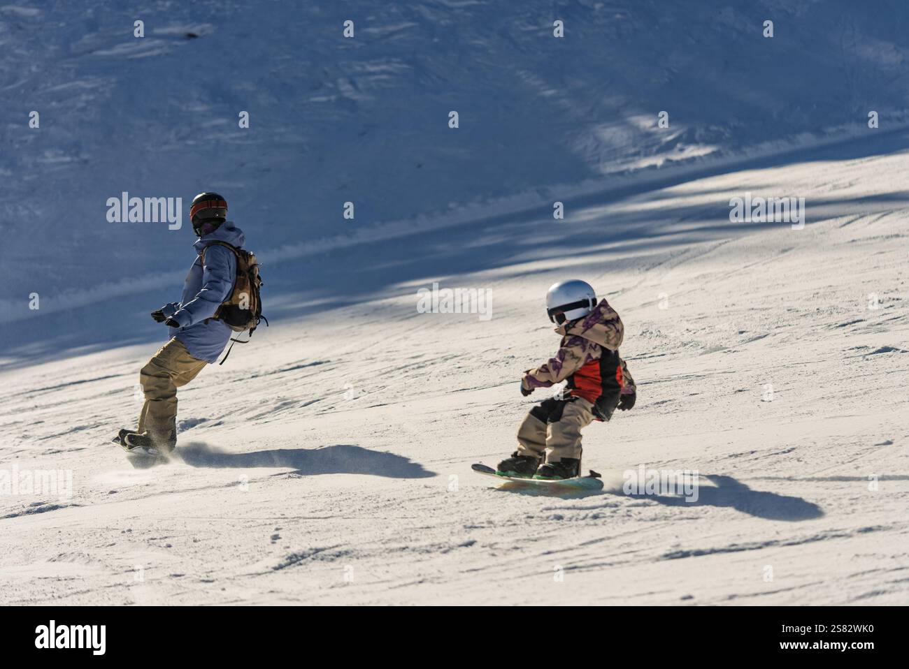 Gruppo di persone che fanno snowboard in montagna in una giornata invernale di sole. Lezioni di snowboard con istruttori locali. I bambini imparano a fare snowboard con un istruttore Foto Stock