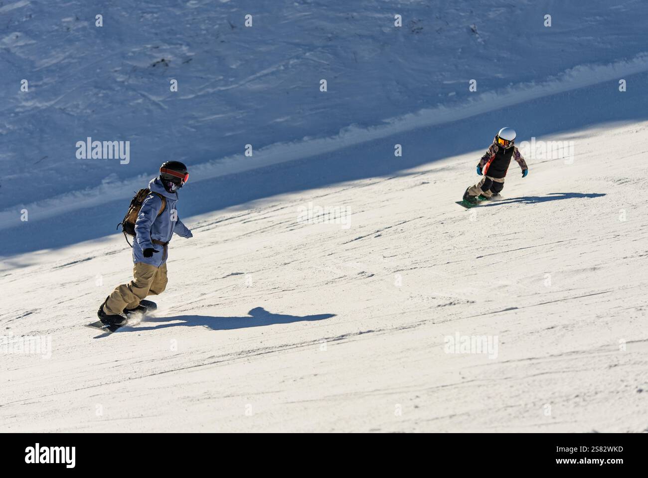 Gruppo di persone che fanno snowboard in montagna in una giornata invernale di sole. Lezioni di snowboard con istruttori locali. I bambini imparano a fare snowboard con un istruttore Foto Stock