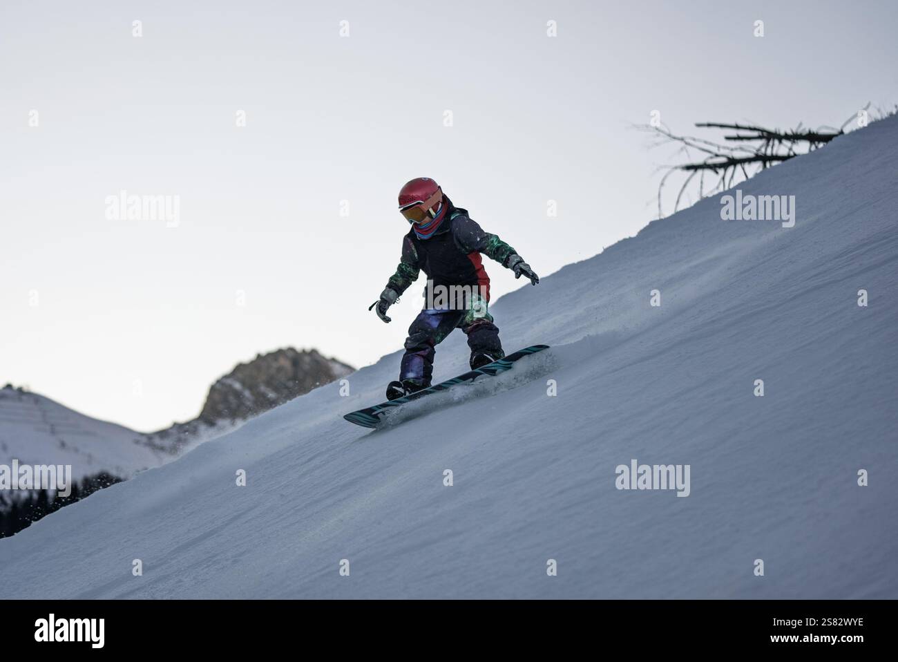 Gruppo di persone che fanno snowboard in montagna in una giornata invernale di sole. Lezioni di snowboard con istruttori locali. I bambini imparano a fare snowboard con un istruttore Foto Stock