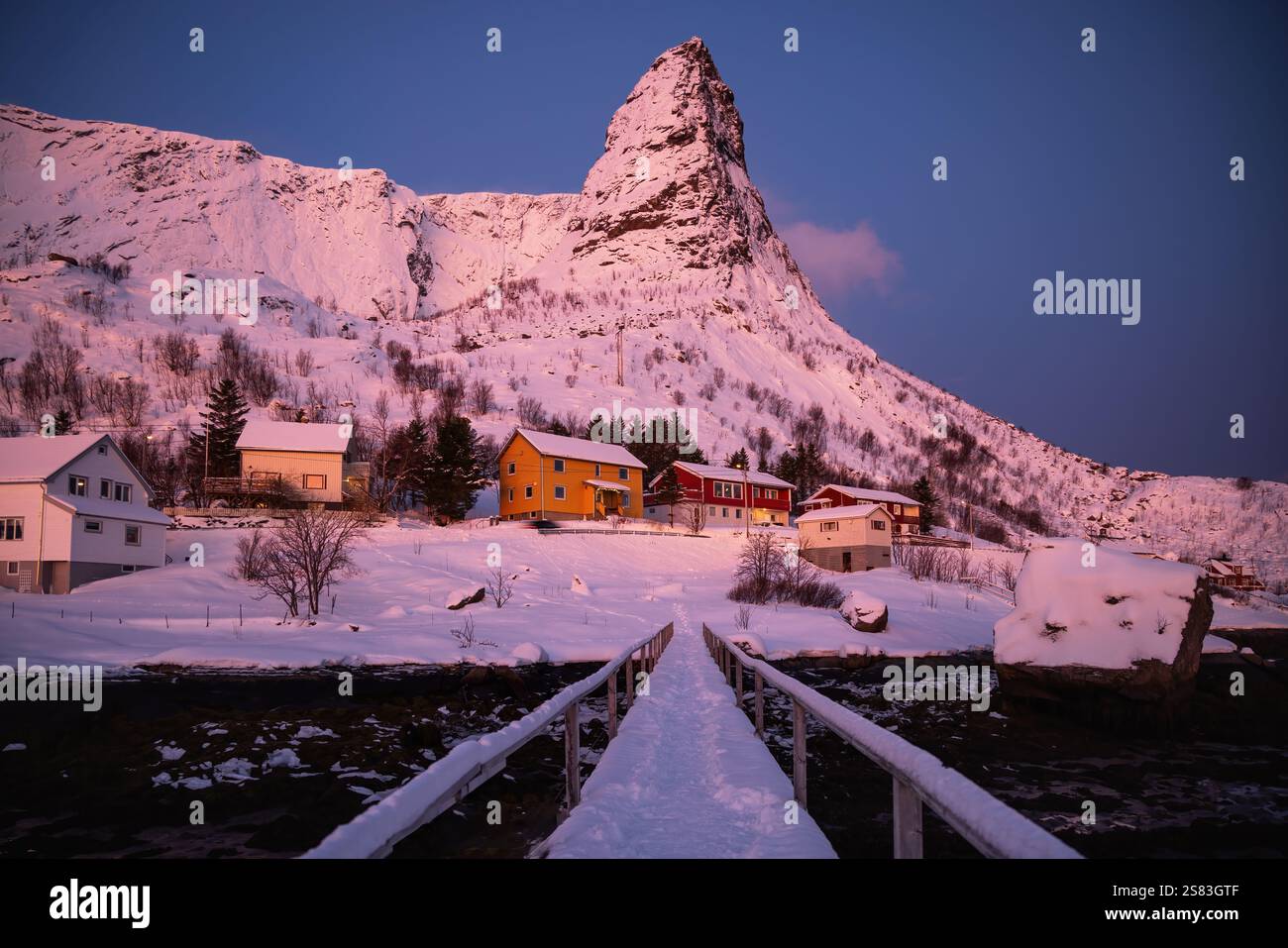 Montagna appuntita di Reine con passerella pedonale e rorbu case nel paesaggio invernale del tramonto , villaggio di Reine, isole Lofoten, Nordland, Artico, Norvegia, Euro Foto Stock