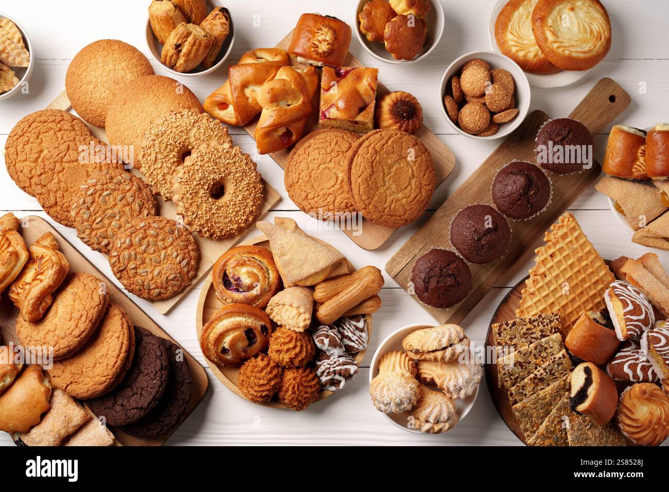 Varietà di prodotti da forno esposti su superfici in legno, tra cui biscotti, pasticcini e dolci per una piacevole riunione Foto Stock