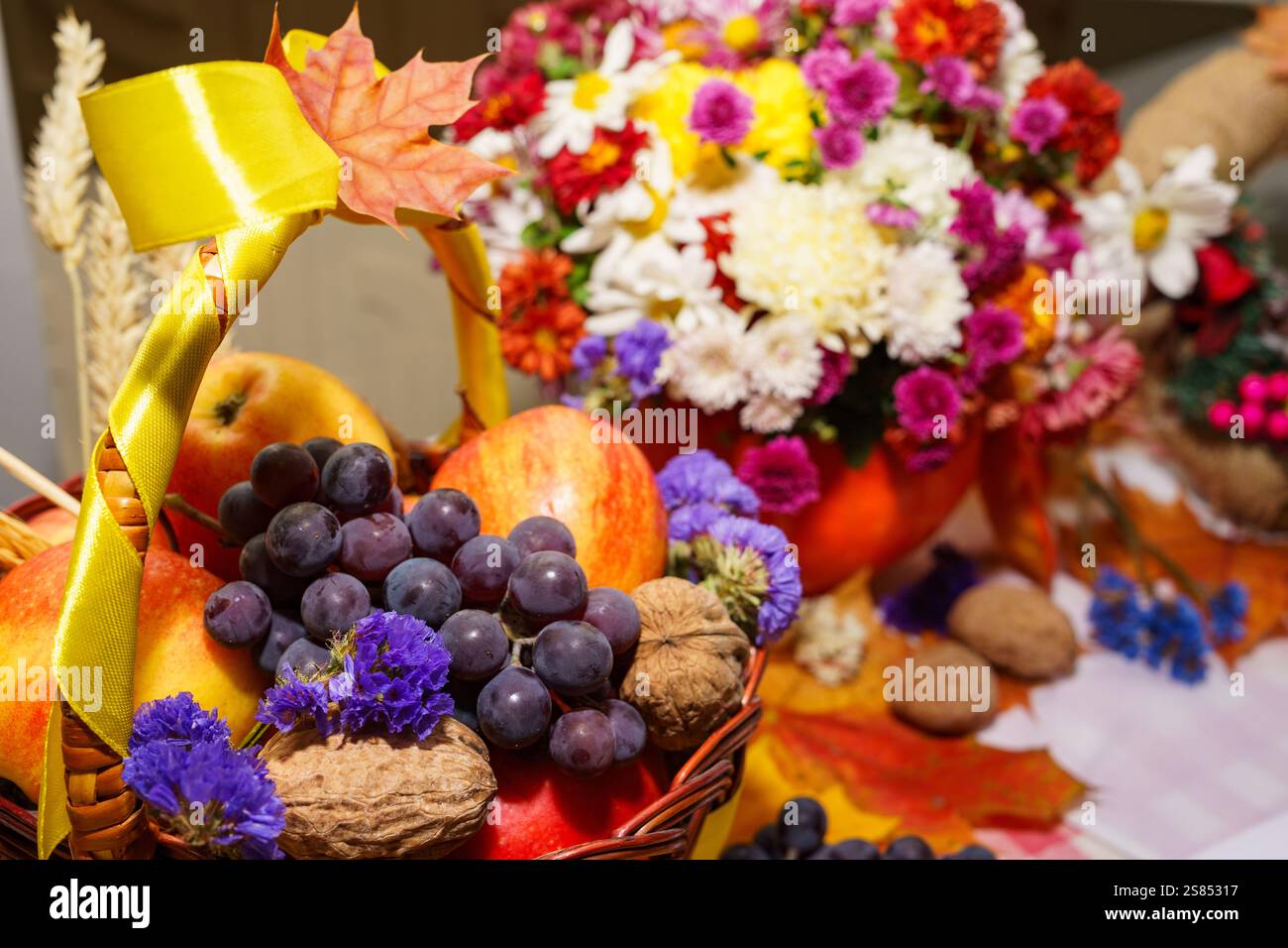 I cesti traboccano di mele, uva e fiori vivaci durante una festa autunnale. L'allestimento mostra i prodotti stagionali e. Foto Stock