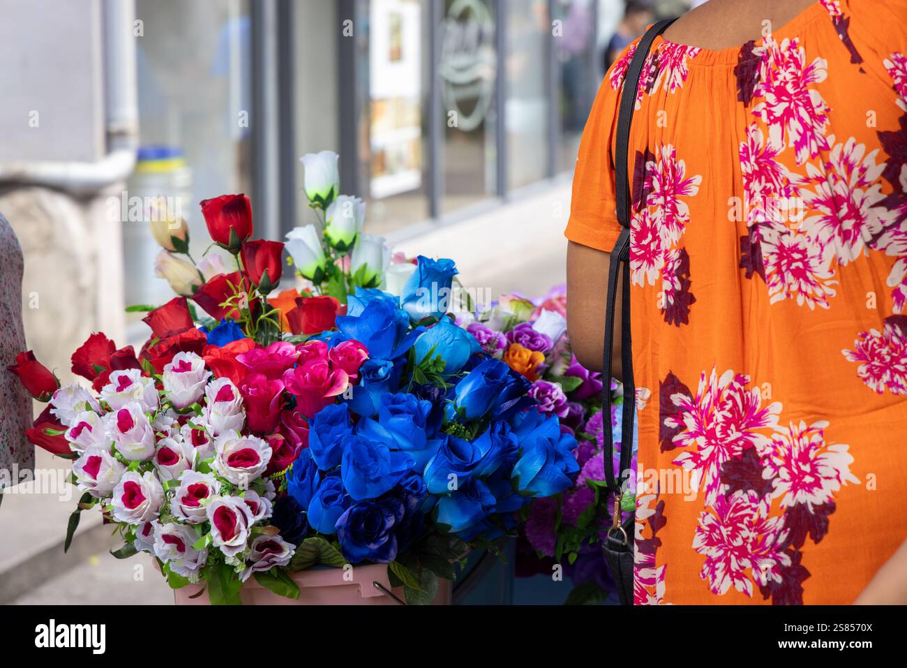 Fiori artificiali da vendere al Selwyn Selwyn-Clake Market di Victoria, Seychelles, con il dorso di una donna che indossa una camicetta fiorita Foto Stock