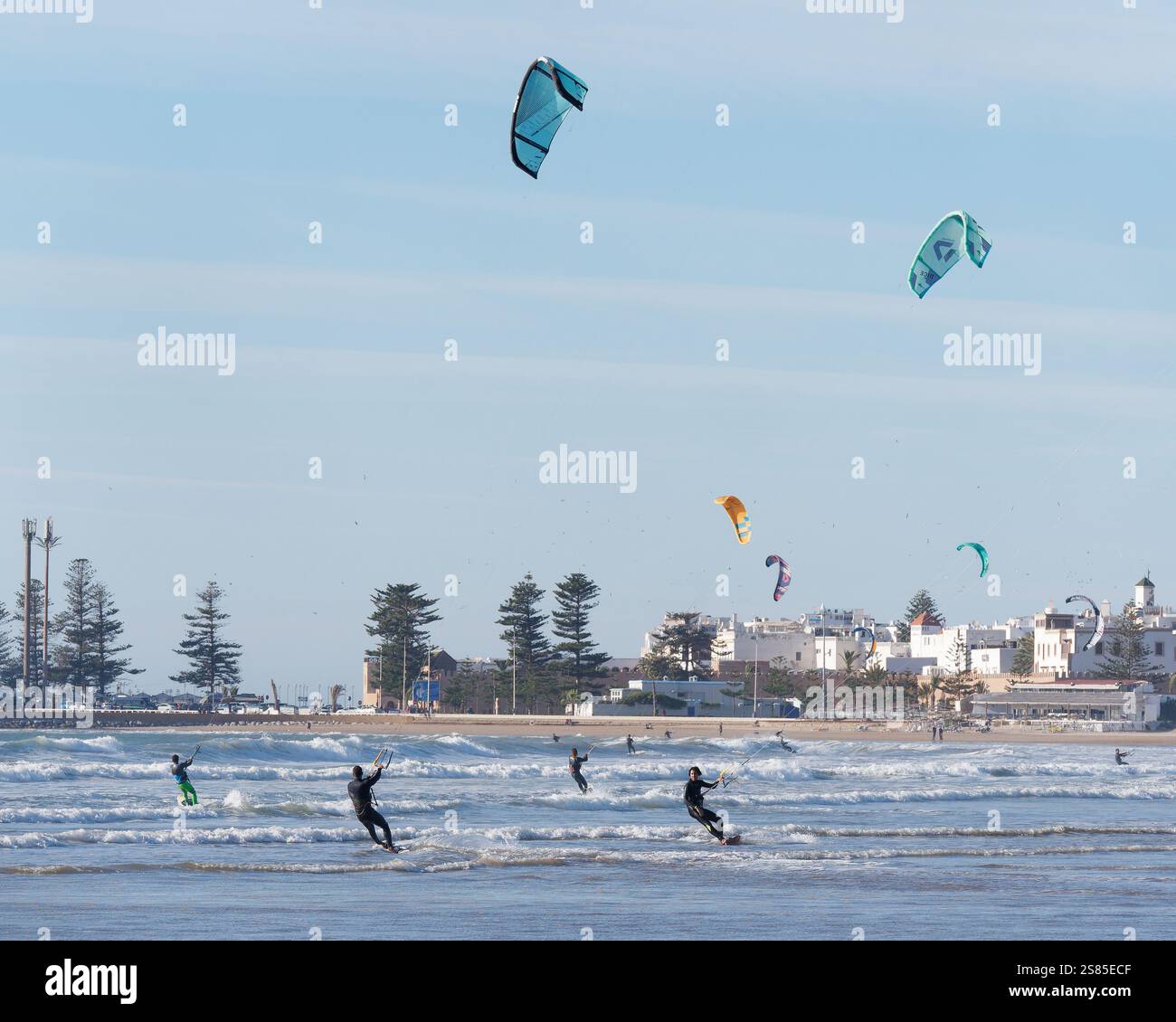 Kite Surfers che scivolano sulle onde del mare con la storica Medina alle spalle nella città di Essaouira, in Marocco. 20 gennaio 2025 Foto Stock