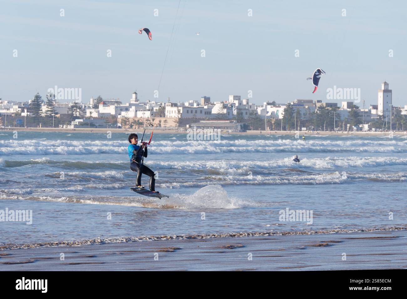 Kite Surfers in mare con la storica Medina alle spalle nella città di Essaouira, in Marocco. 20 gennaio 2025 Foto Stock