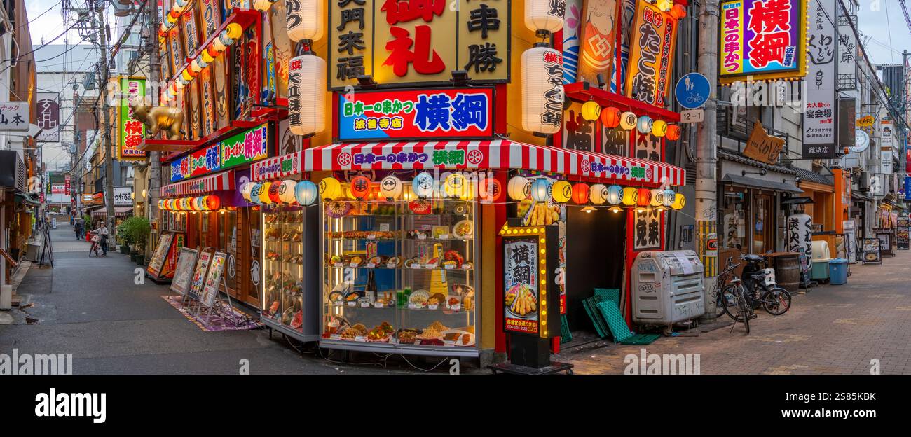 Vista delle colorate facciate di negozi e ristoranti a Dotonbori, vivace quartiere dei divertimenti vicino al fiume, Osaka, Honshu, Giappone Foto Stock