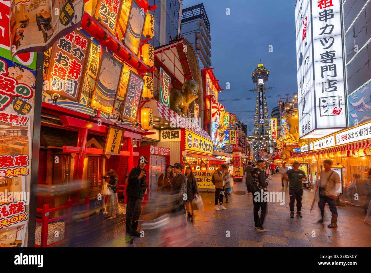 Vista della Torre Tsutenkaku e dei ristoranti con luci al neon al crepuscolo nell'area di Shinsekai, Osaka, Honshu, Giappone Foto Stock