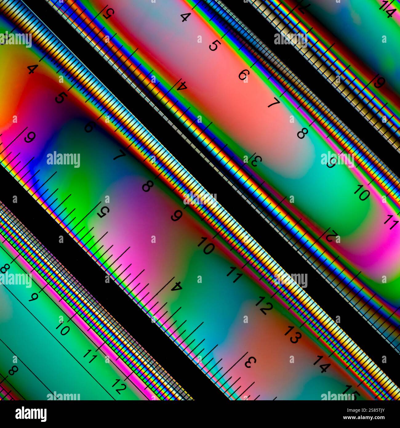 Quattro righelli in plastica di un set di geometria, fotografati con luce a polarizzazione incrociata, che mostrano una gamma di colori Foto Stock