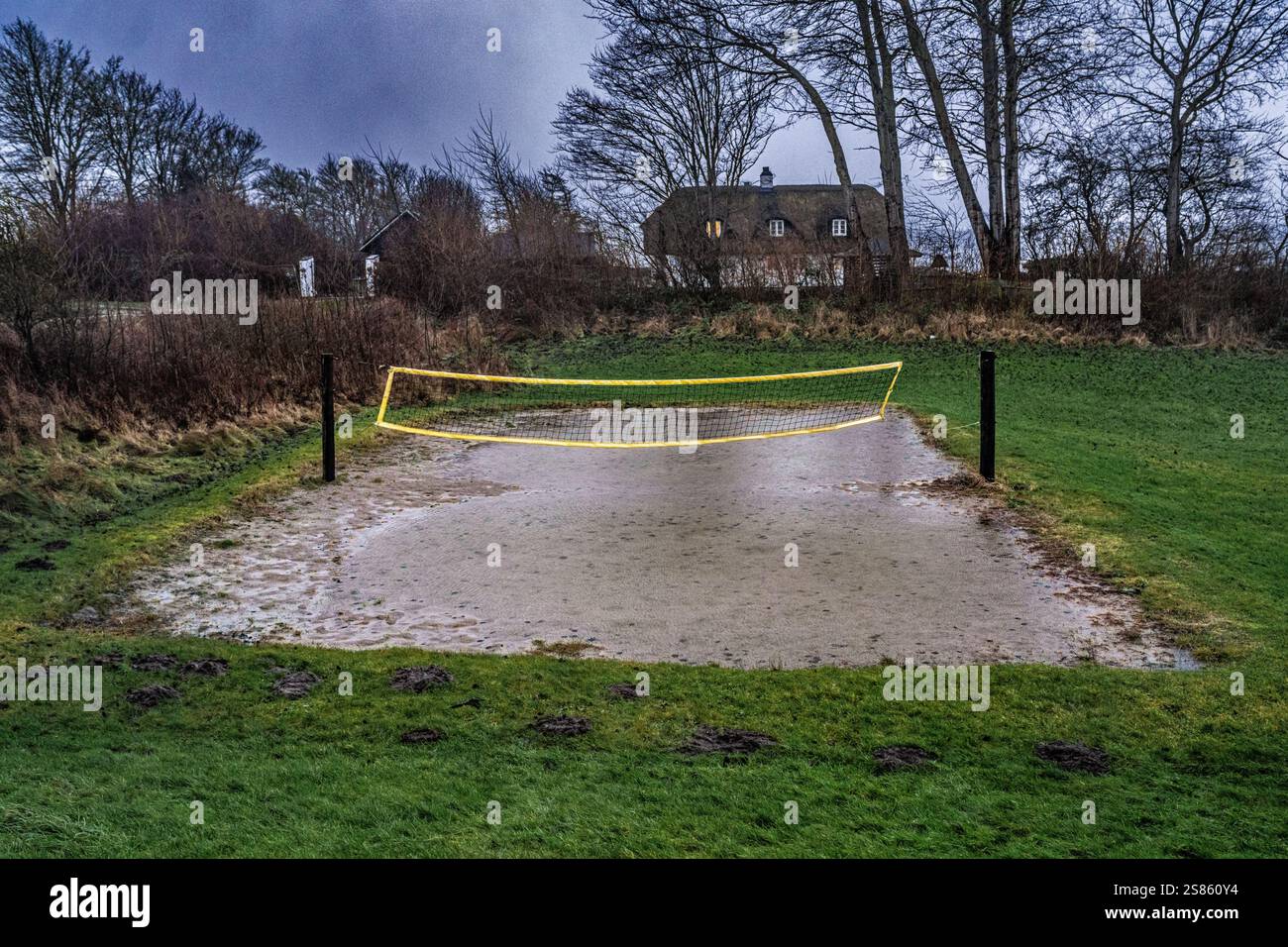 Campo sportivo all'aperto inondato con una rete, circondato da erba e campagna in un ambiente rurale durante le piogge. Mostra gli effetti del natur Foto Stock