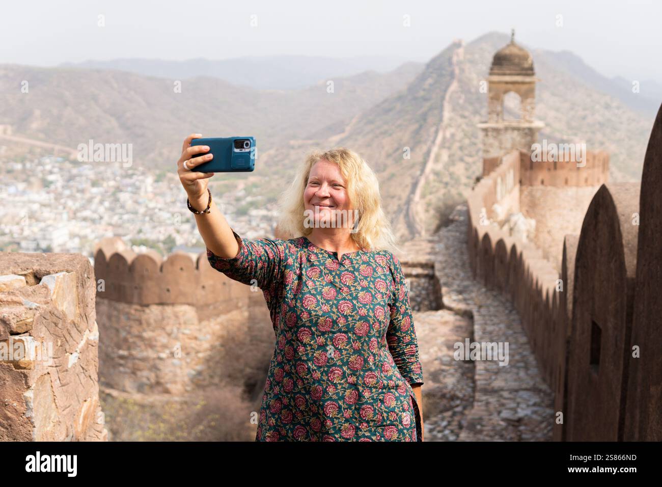 Giovane donna bionda che si fa selfie sulla grande parete di Jaipur nel Rajasthan. Felice sorridente turista europeo che esplora l'India. Foto Stock