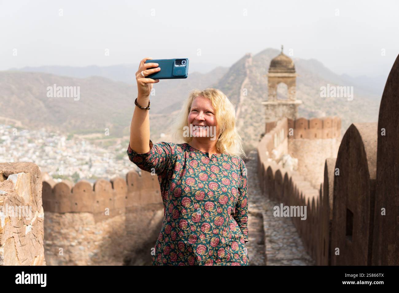 Giovane donna bionda che si fa selfie sulla grande parete di Jaipur nel Rajasthan. Felice sorridente turista europeo che esplora l'India. Foto Stock
