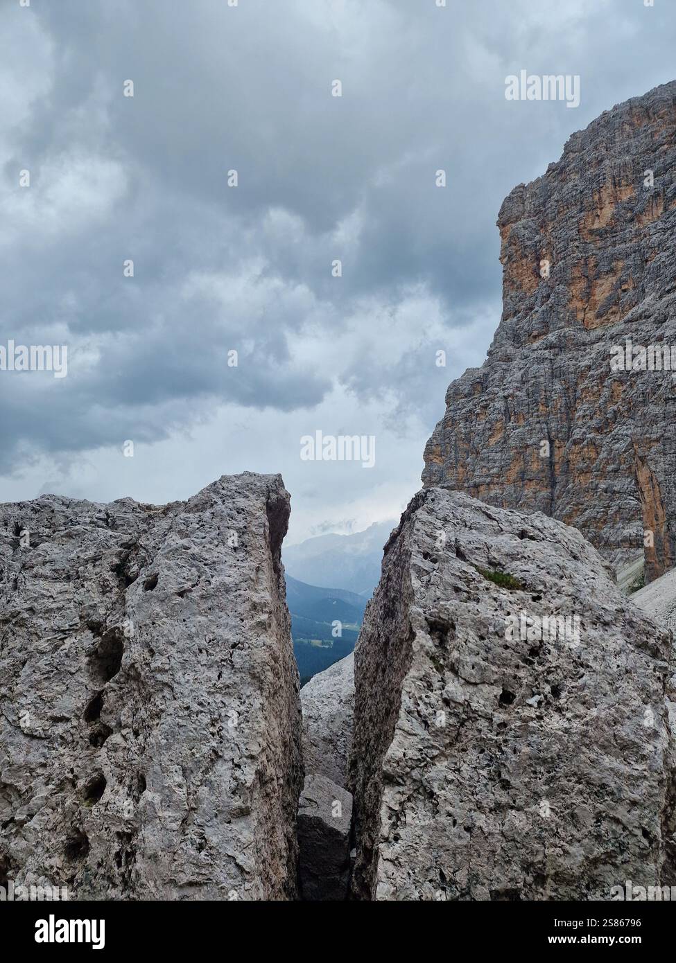 Primo piano di rocce aspre con una spaccatura tra loro, contro un cielo nuvoloso drammatico, le Dolomiti italiane. Caratteristiche geologiche e consistenze delle rocce Foto Stock