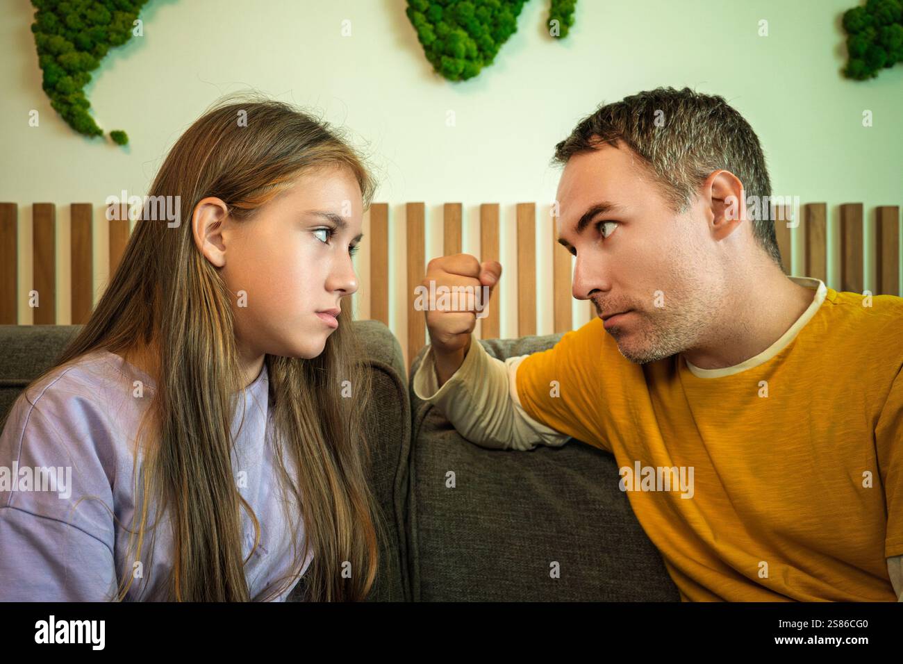 Il padre mostra il pugno a sua figlia, rimproverandola per il suo cattivo comportamento. Concetto di genitorialità rigoroso Foto Stock