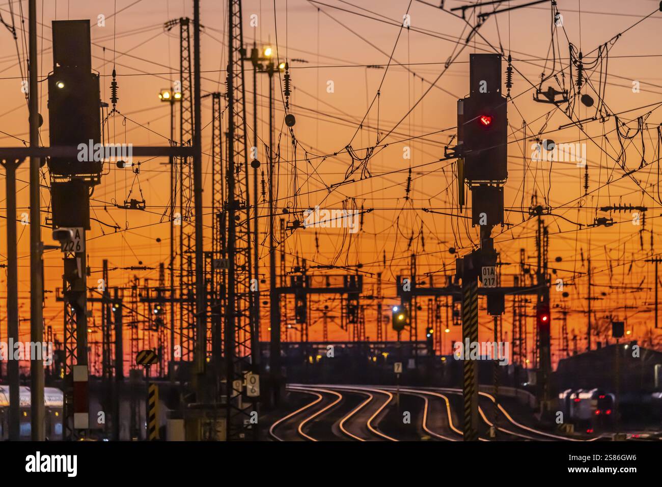 Piazzale in pista la sera con il tramonto. Stazione centrale di Francoforte sul meno con rotaie, montanti di linea e sistemi di segnalazione. Foto simbolica dell'infrastruttura Foto Stock