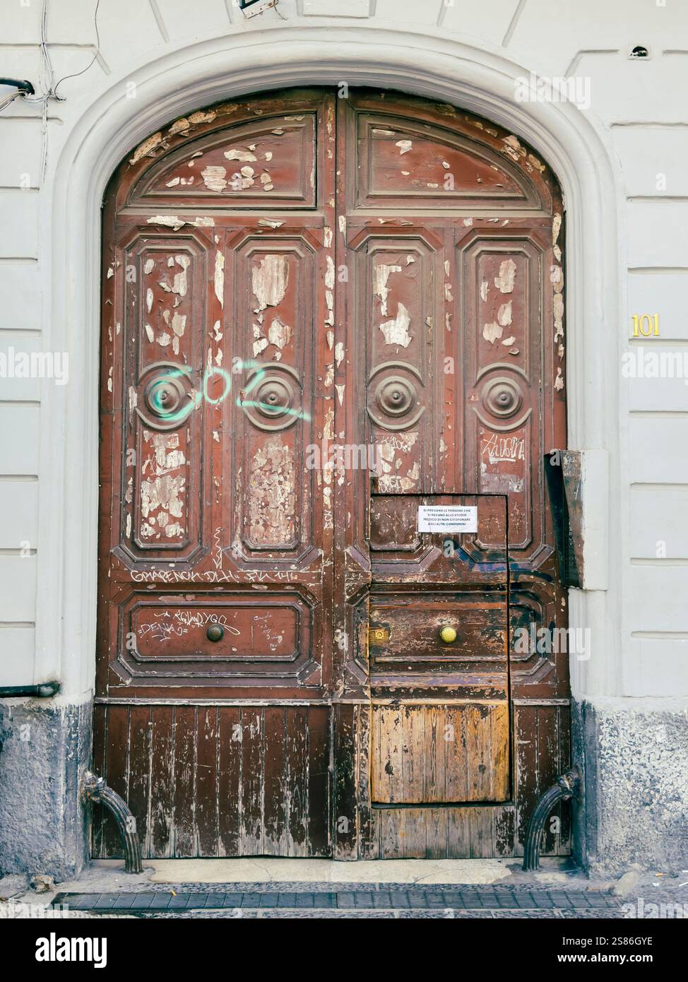 Nel cuore di Napoli, in Piazza Garibaldi, una porta in legno d'epoca è una silenziosa testimonianza dei ritmi sempre mutevoli della città. Foto Stock