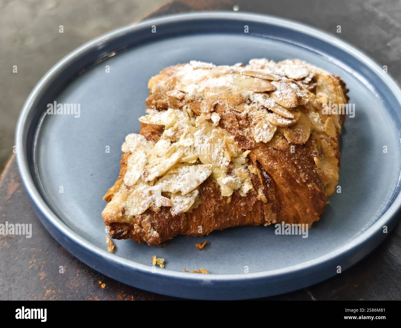 Un piatto di croissant con una spolverata di zucchero a velo e fiocchi di mandorle Foto Stock