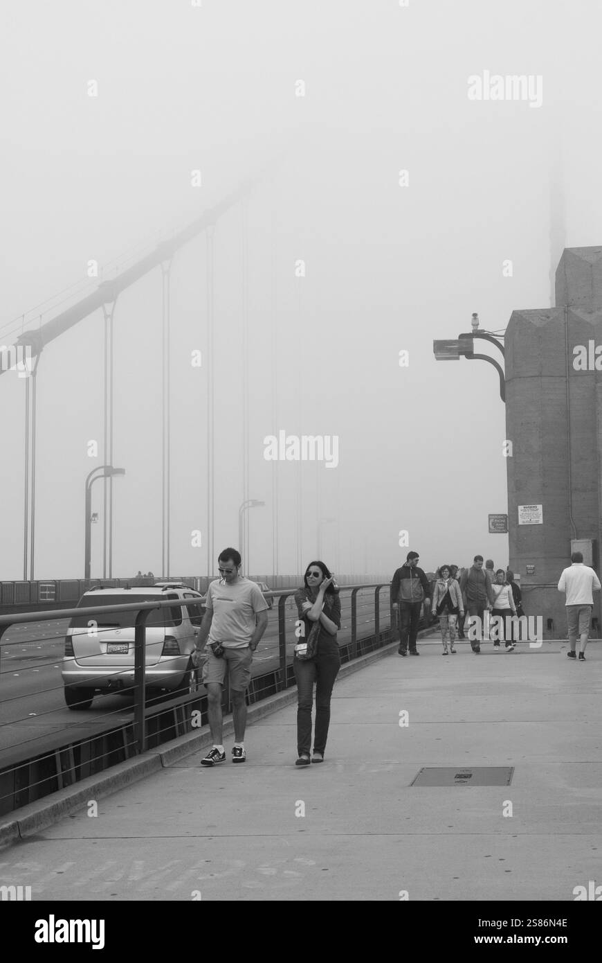 I turisti camminano attraverso la fitta nebbia attraverso il Golden Gate Bridge di San Francisco, California, Stati Uniti, un'attrazione famosa in tutto il mondo. Foto Stock