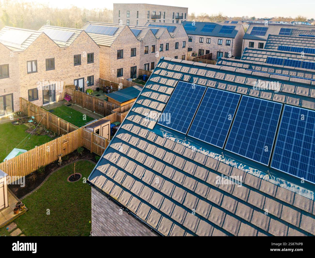 Il tetto di una fila di case di nuova costruzione in un cantiere con tetto integrato o pannelli solari a tetto per un'energia economica e sostenibile in un ambiente moderno, Foto Stock