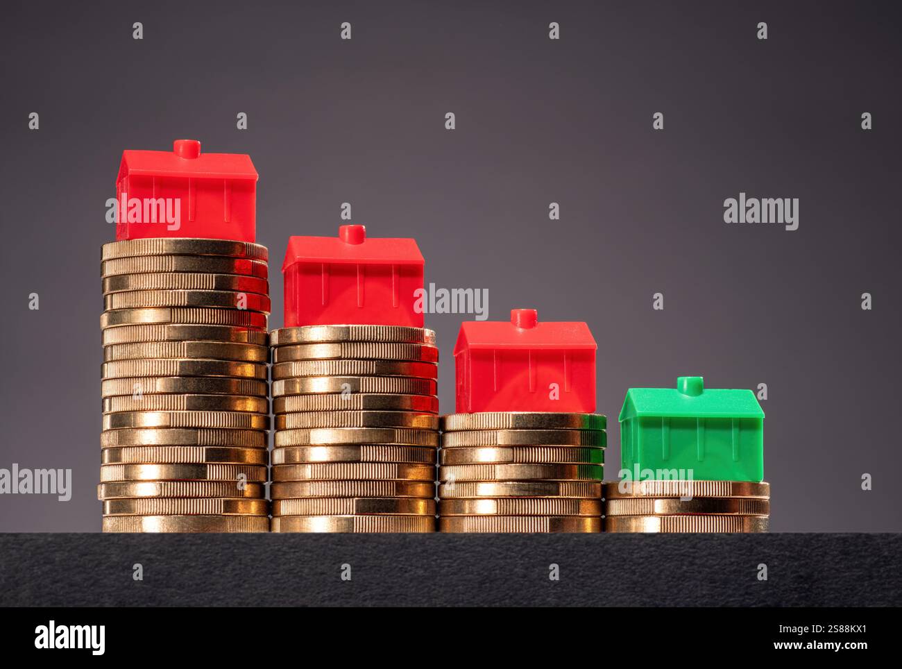 Concetto di calo dei prezzi immobiliari. Case su pile di soldi in pendenza. Foto Stock