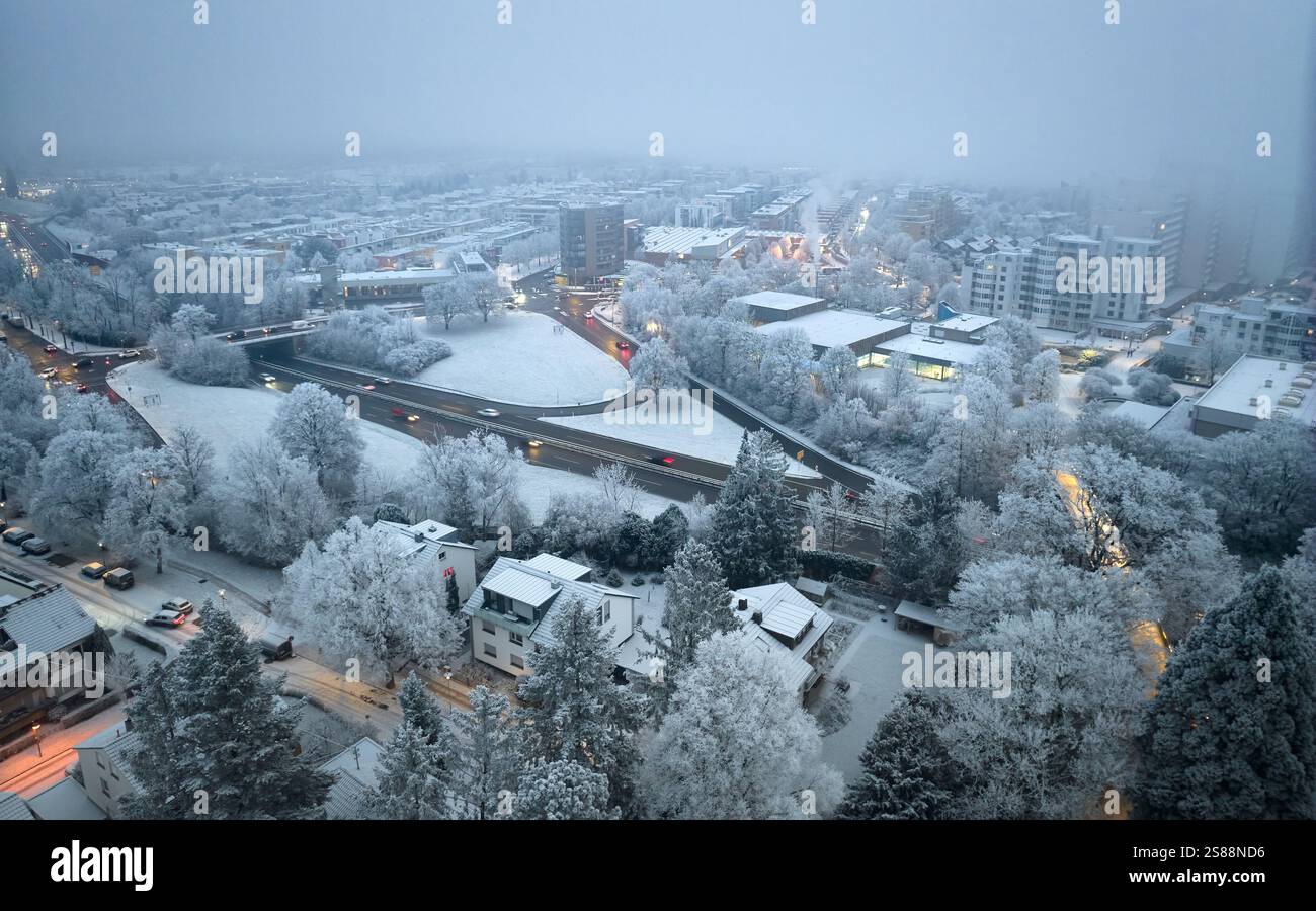 Paesaggio urbano innevato con strade trafficate e crocevia al crepuscolo mattutino a Rushour a Kornwestheim, Baden-Wuerttemberg, Germania Foto Stock