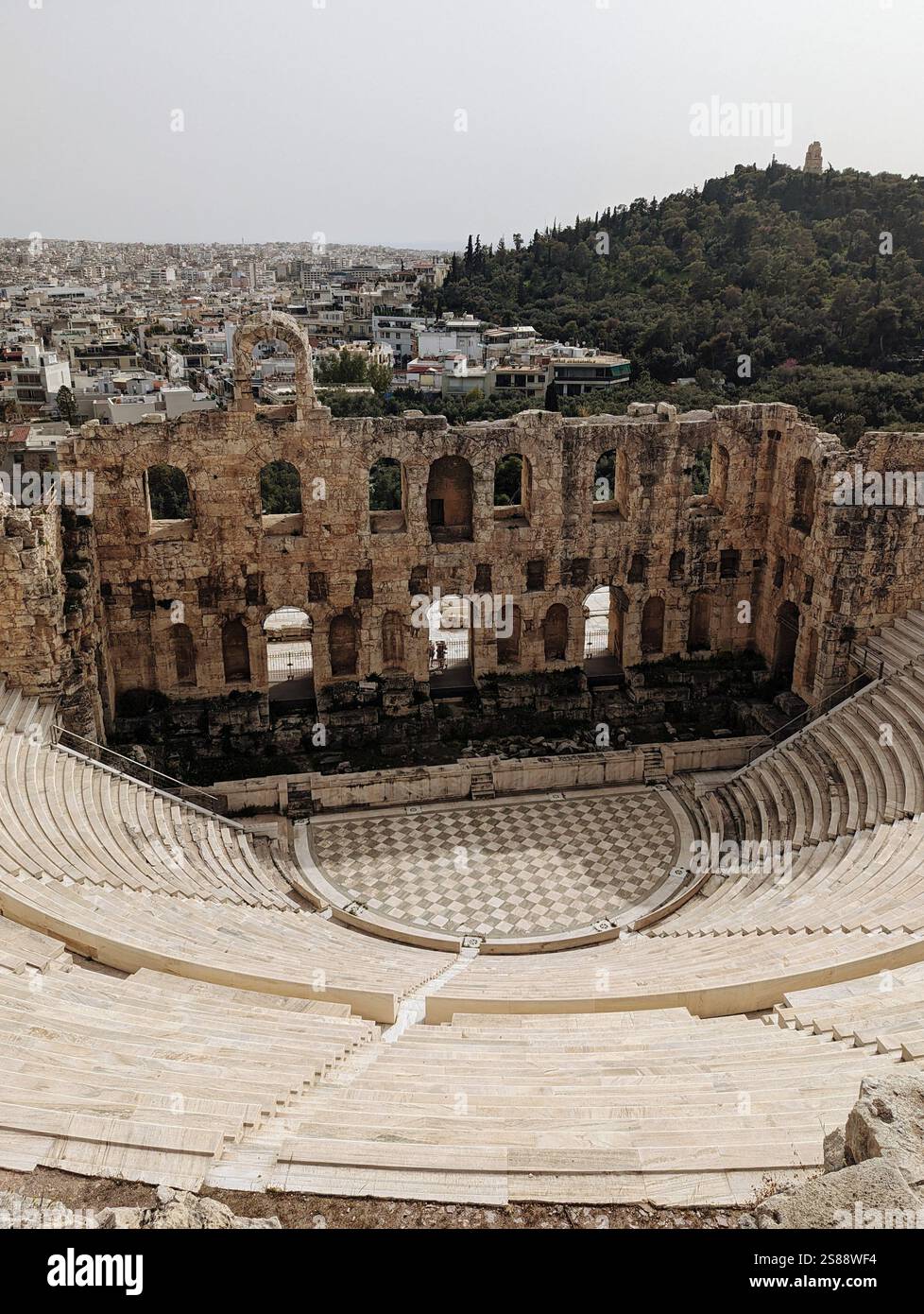 L'Odeon di Erode Attico, un antico teatro ateniese ancora in piedi contro il tempo, affacciato sulla città e sulle colline lussureggianti. - Immagine stock catturata con smartphone
